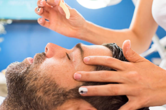A therapist performs a facial treatment on a reclining client in a spa setting.