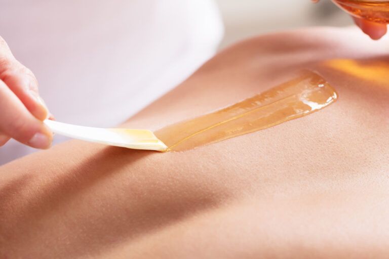 Wax strip being removed from skin during a waxing treatment