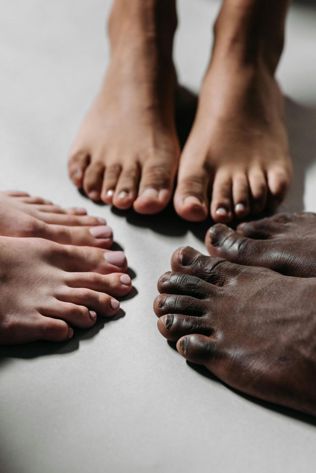 Four pairs of bare feet arranged in a circle on a light surface