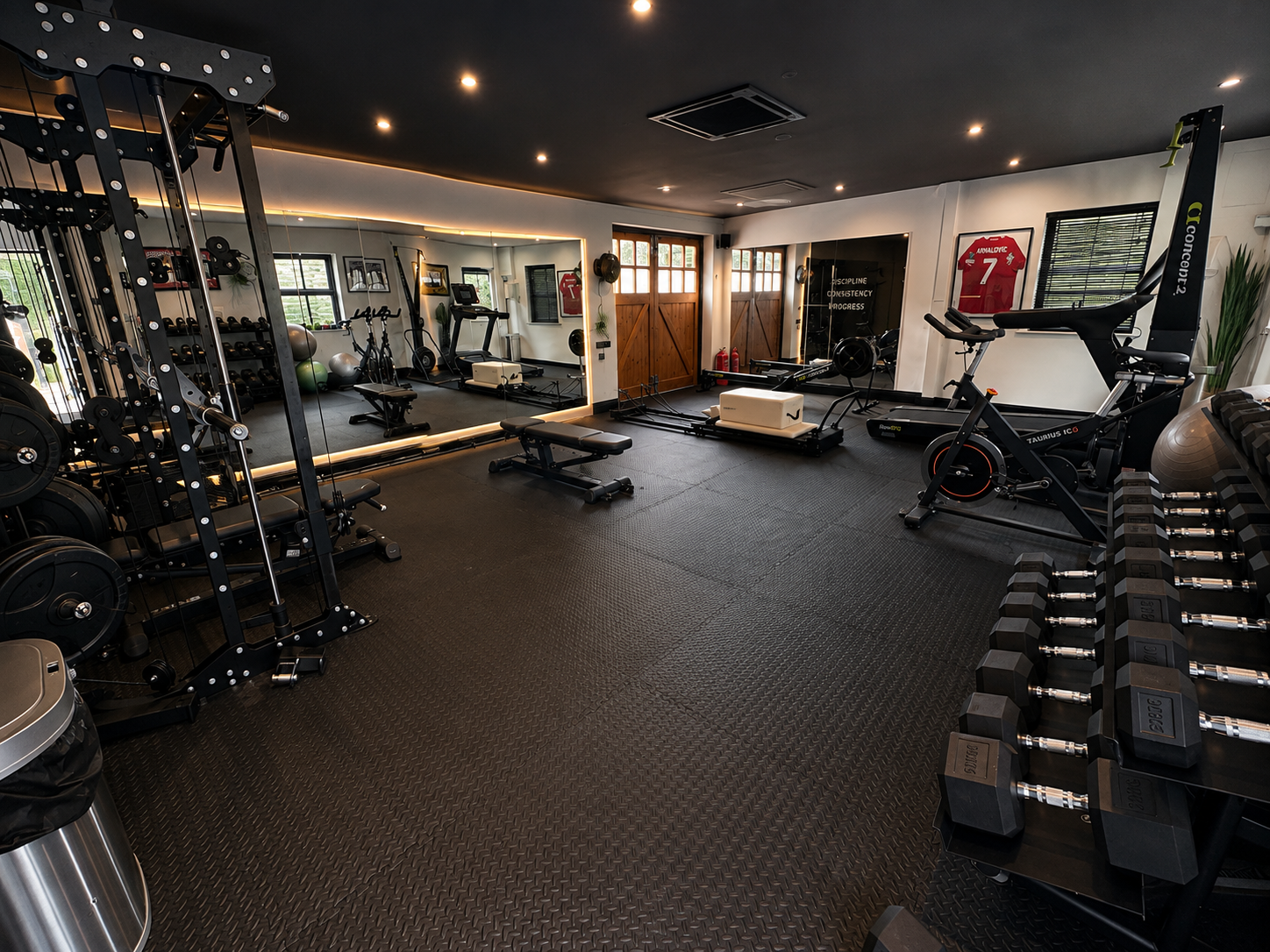 Row of colorful dumbbells on a shelf in a gym setting.