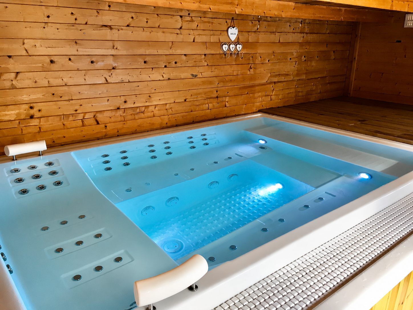 Wooden cabin with jacuzzi, white towels, and exterior view through open glass door.