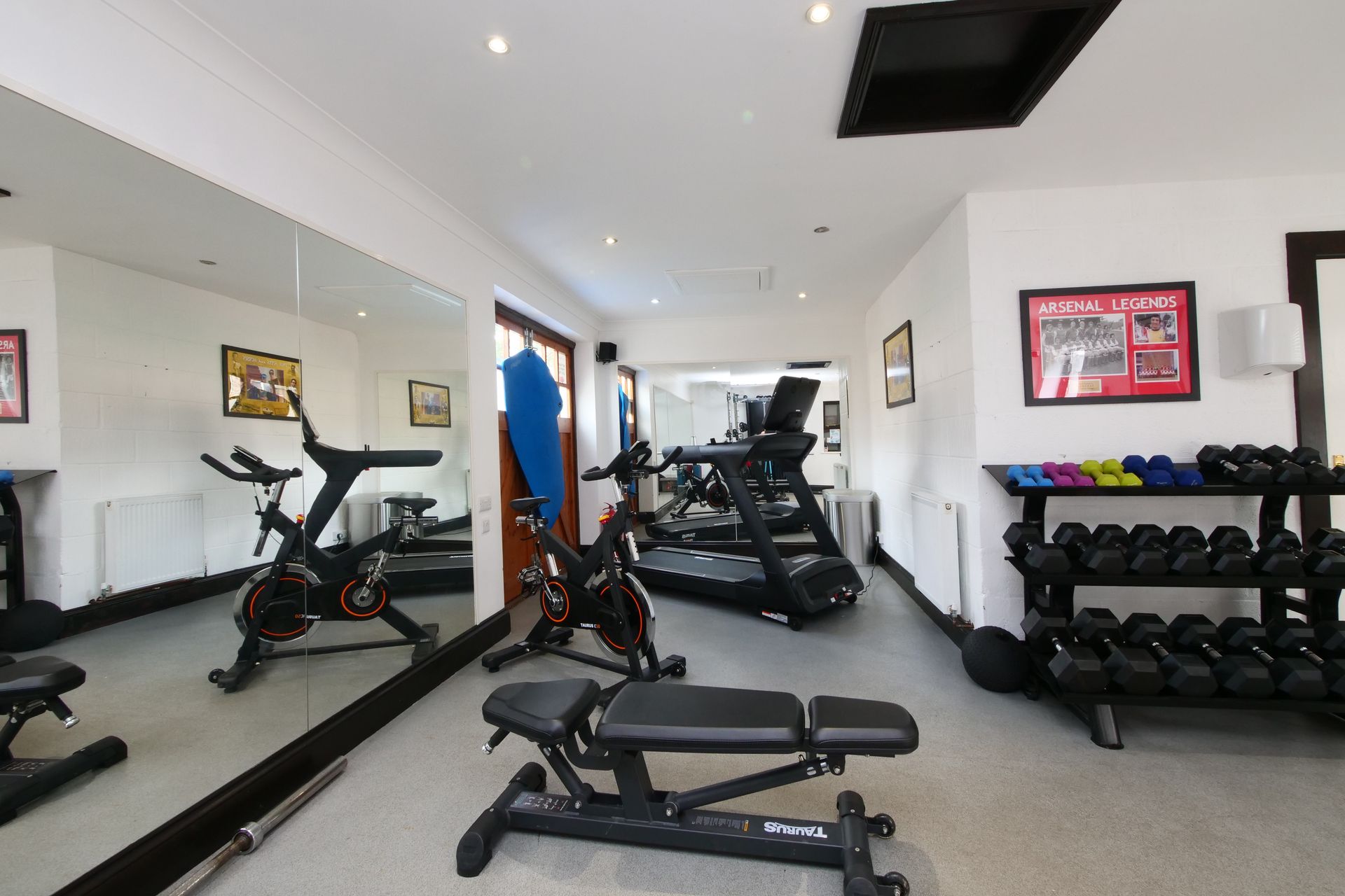 Gym with exercise equipment, including treadmills, weights, stationary bikes, and a bench.