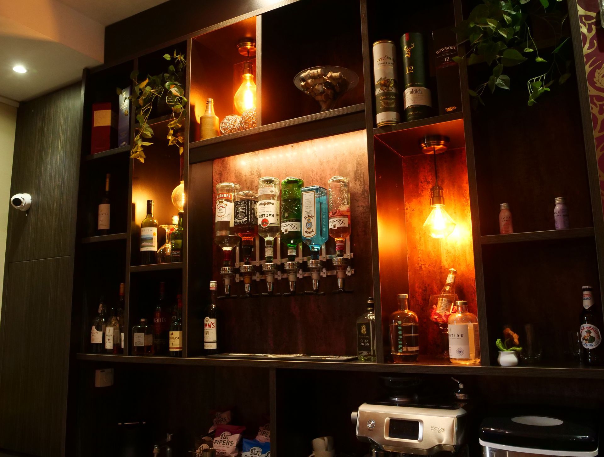 Bar shelf with liquor bottles, plants, and warm lighting in a York hotel
