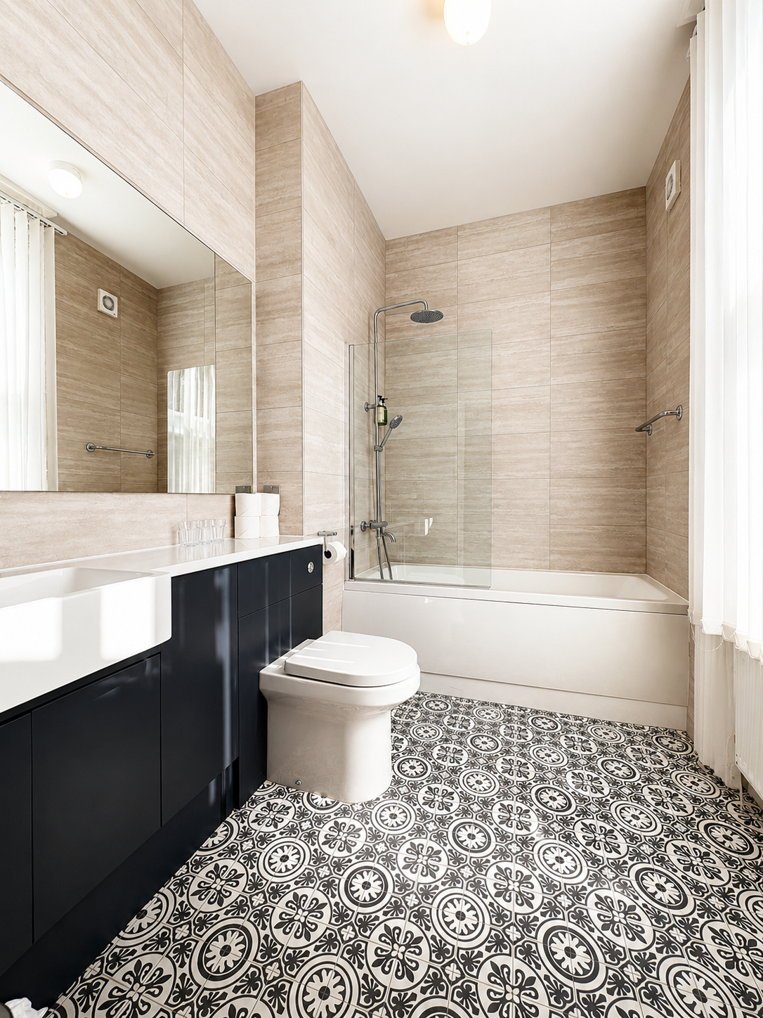 Modern bathroom with white fixtures, glass shower, and neutral tile.