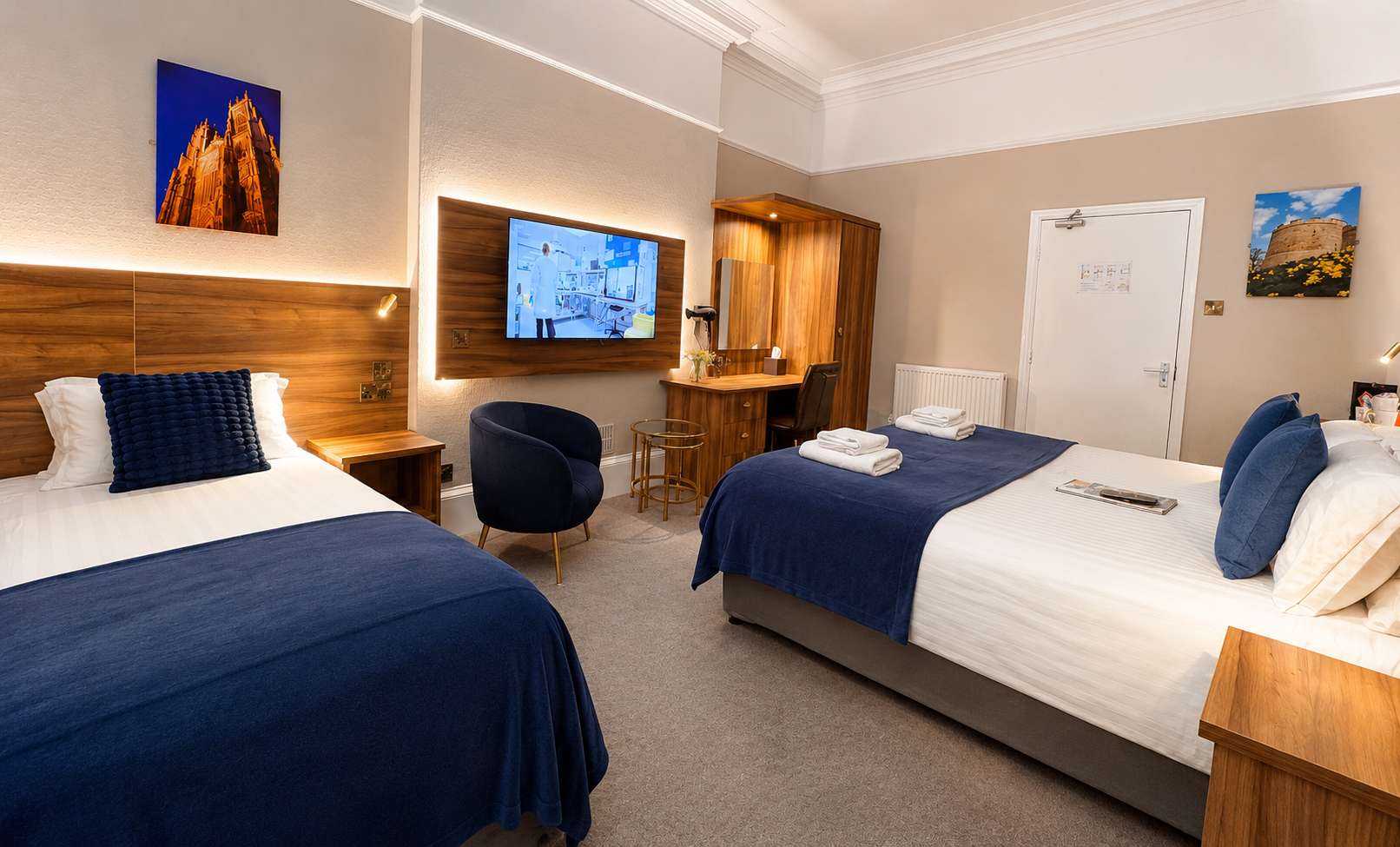 Bedroom with a king-sized bed, small TV, and a black armchair. There's a balcony door.