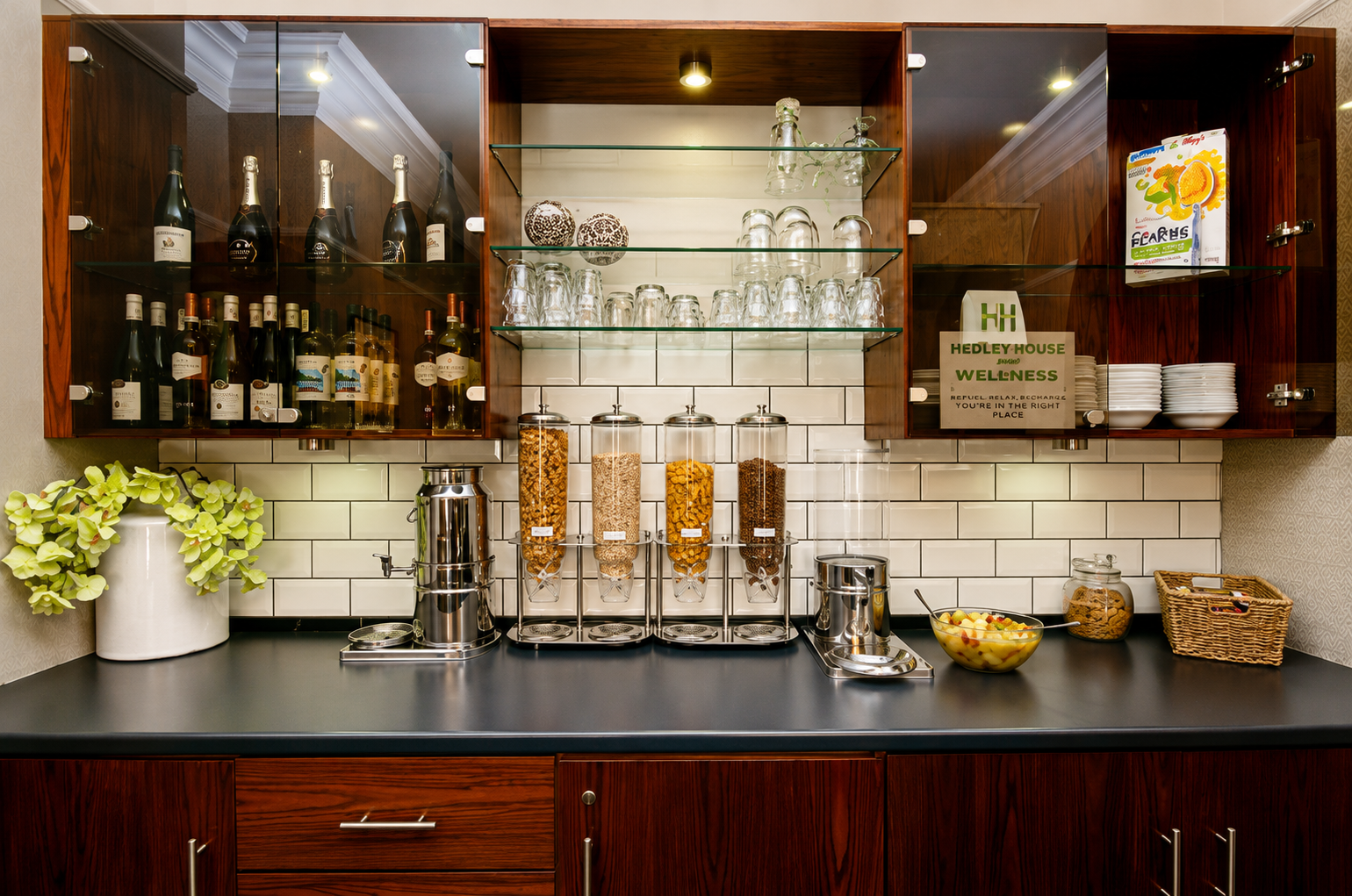 Breakfast bar with cereal dispensers, glassware, and cabinets filled with food and drink.