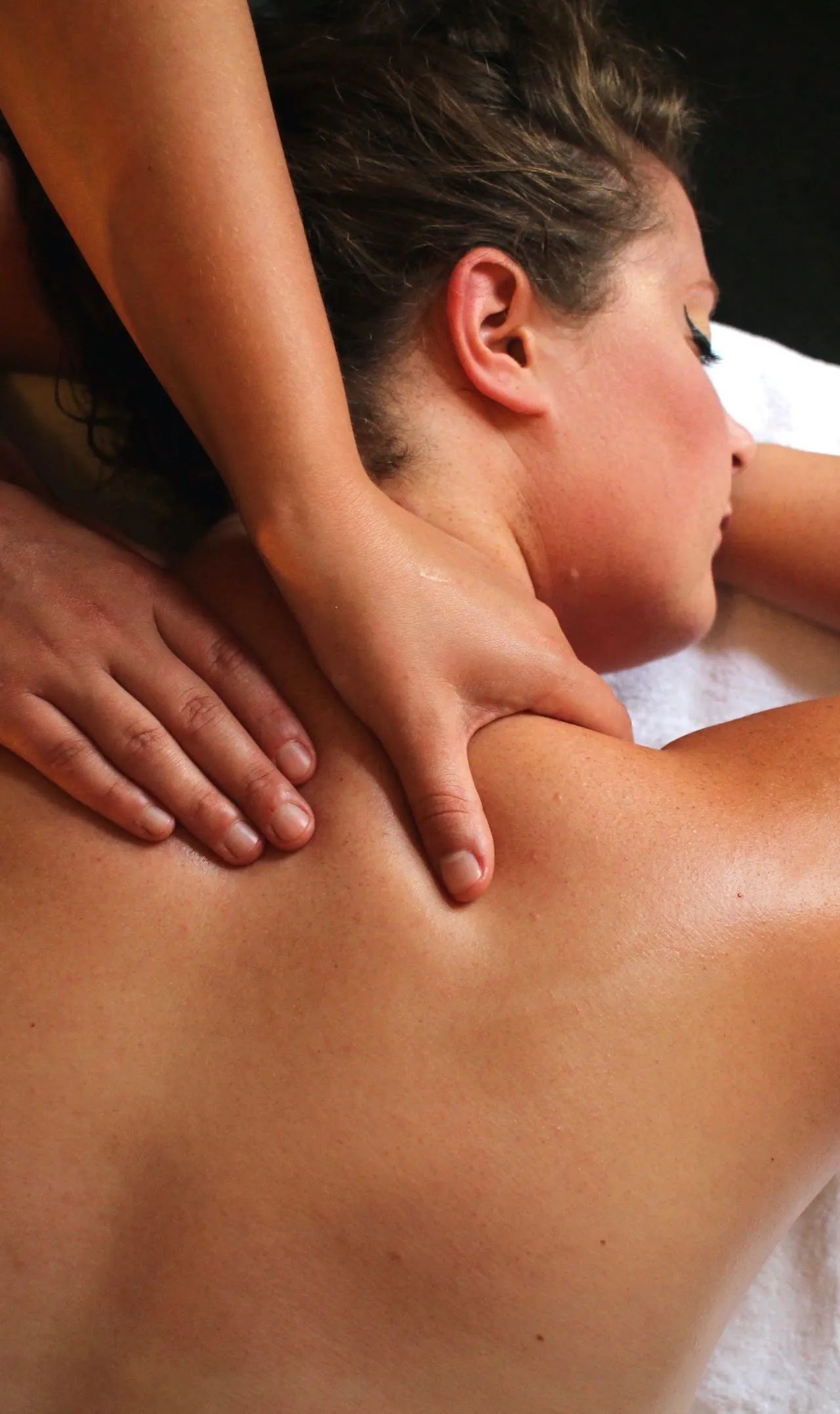 Woman receiving a back massage at a spa, with hands on her shoulders and back.