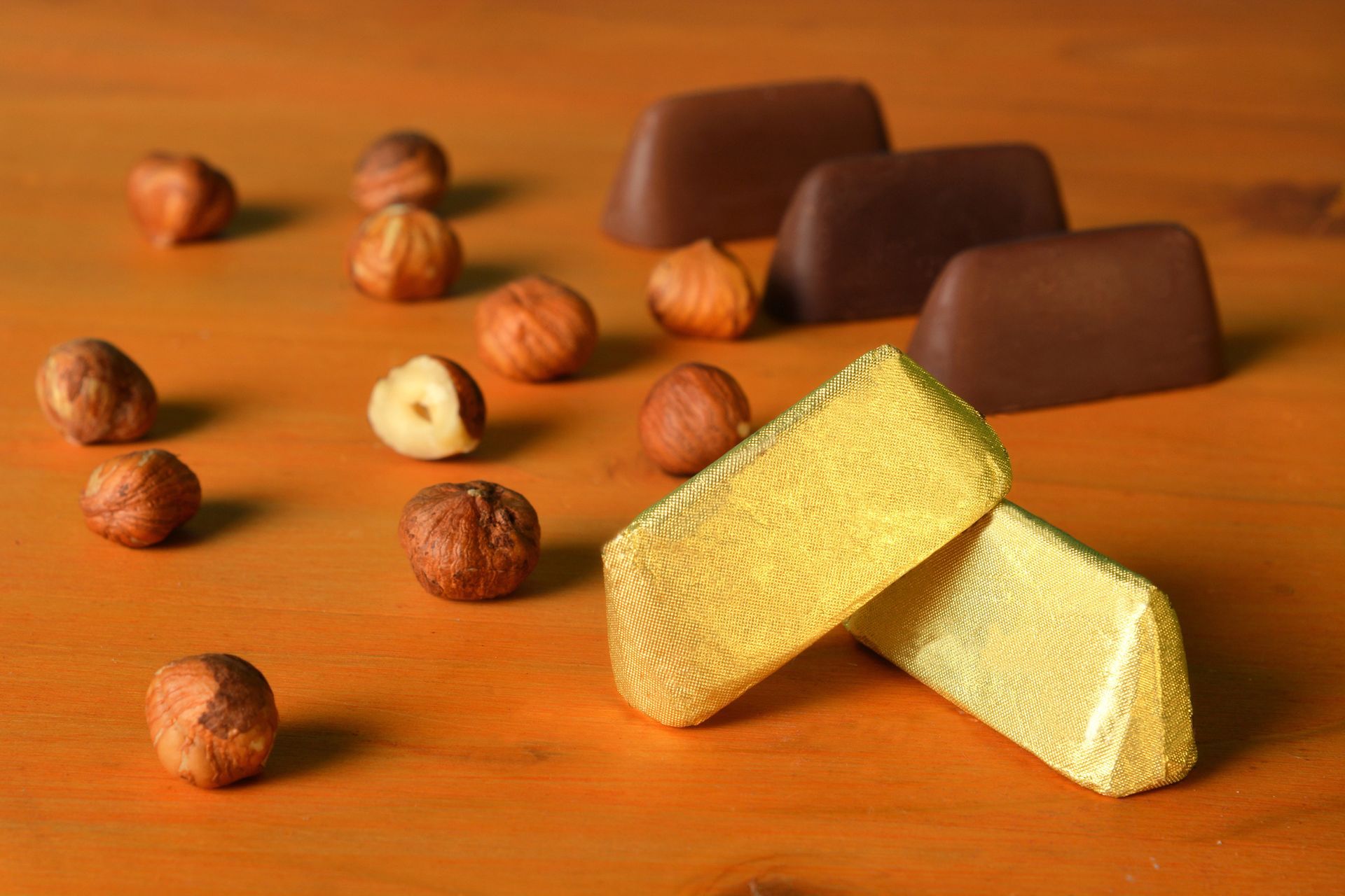 Cioccolatini assortiti e nocciole su un vassoio di legno, con pezzi di cioccolato fondente