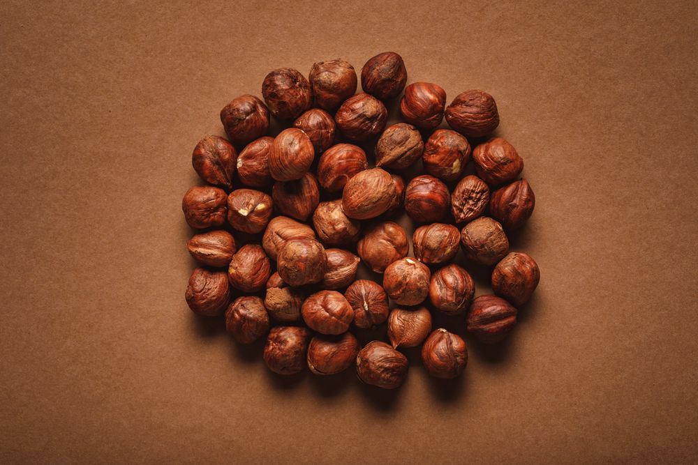 Un mucchio di nocciole marroni disposte a cerchio su uno sfondo marrone.