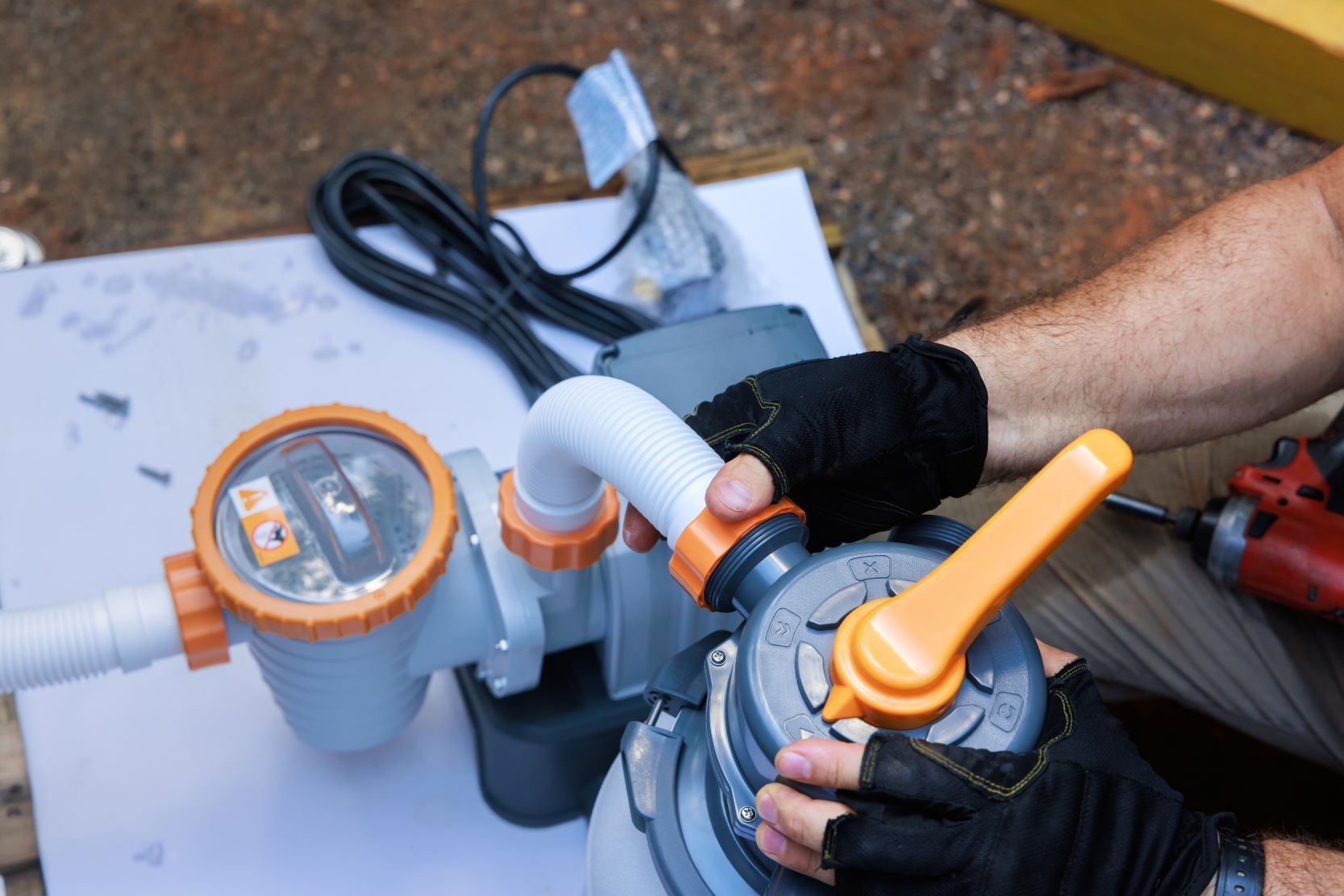 A Man Is Working On A Pool Pump With A Drill