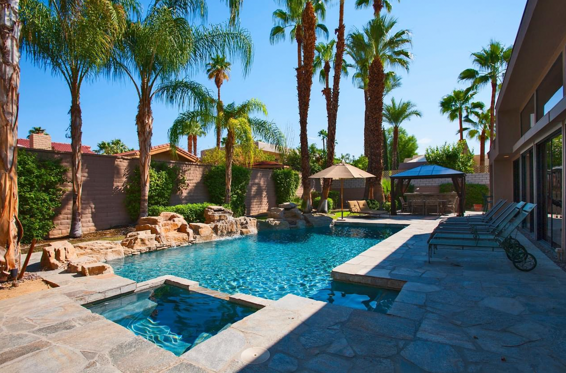 A large swimming pool surrounded by palm trees and chairs
