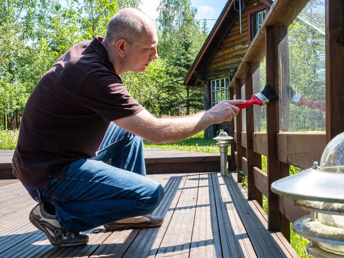 Worker paints a wooden patio