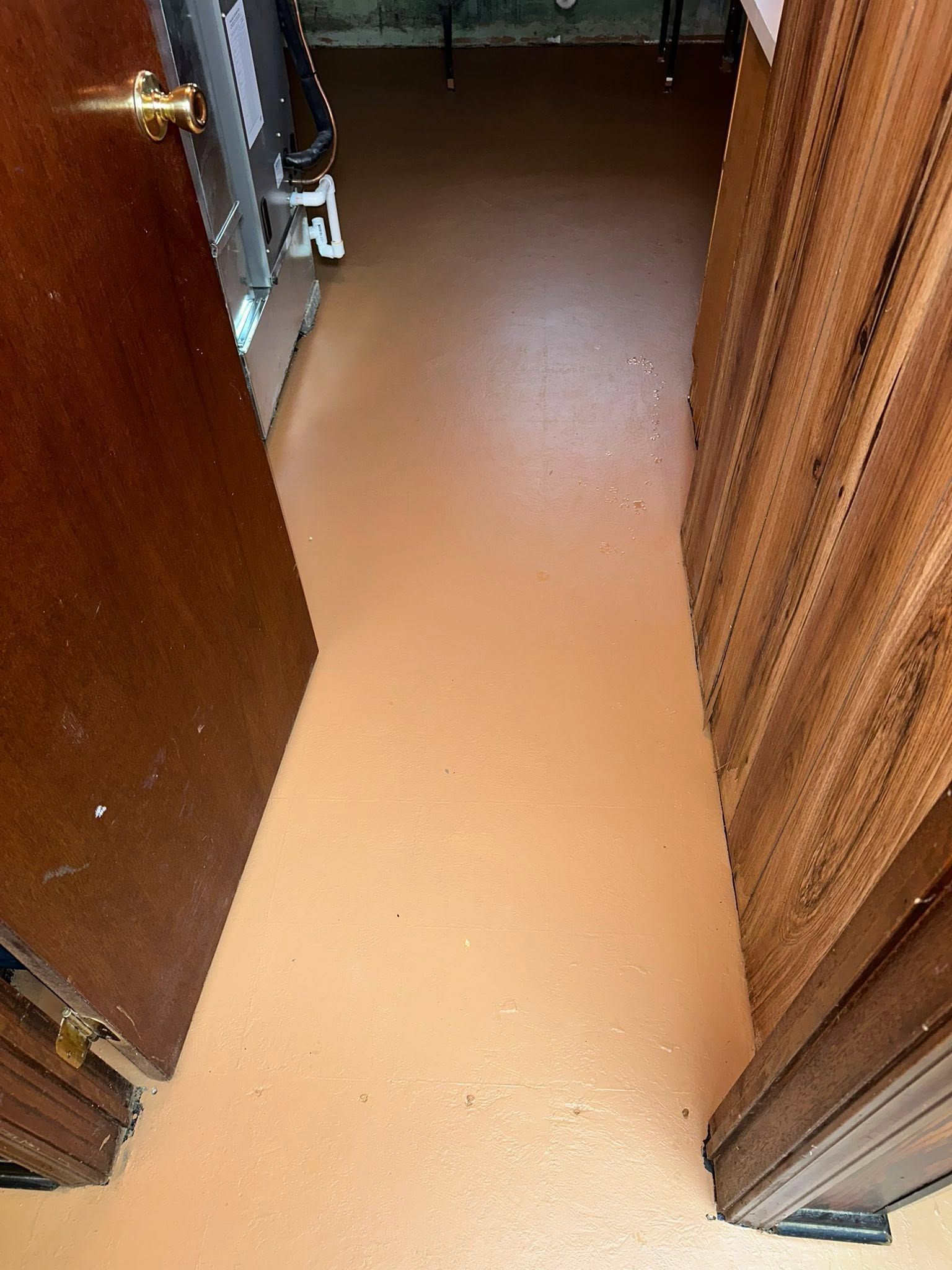 Narrow hallway with tan floor, open wooden doors, and curtains on the right.