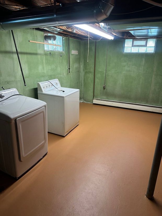 Basement laundry room with washer, dryer, tan floor, green walls, and fluorescent lights.