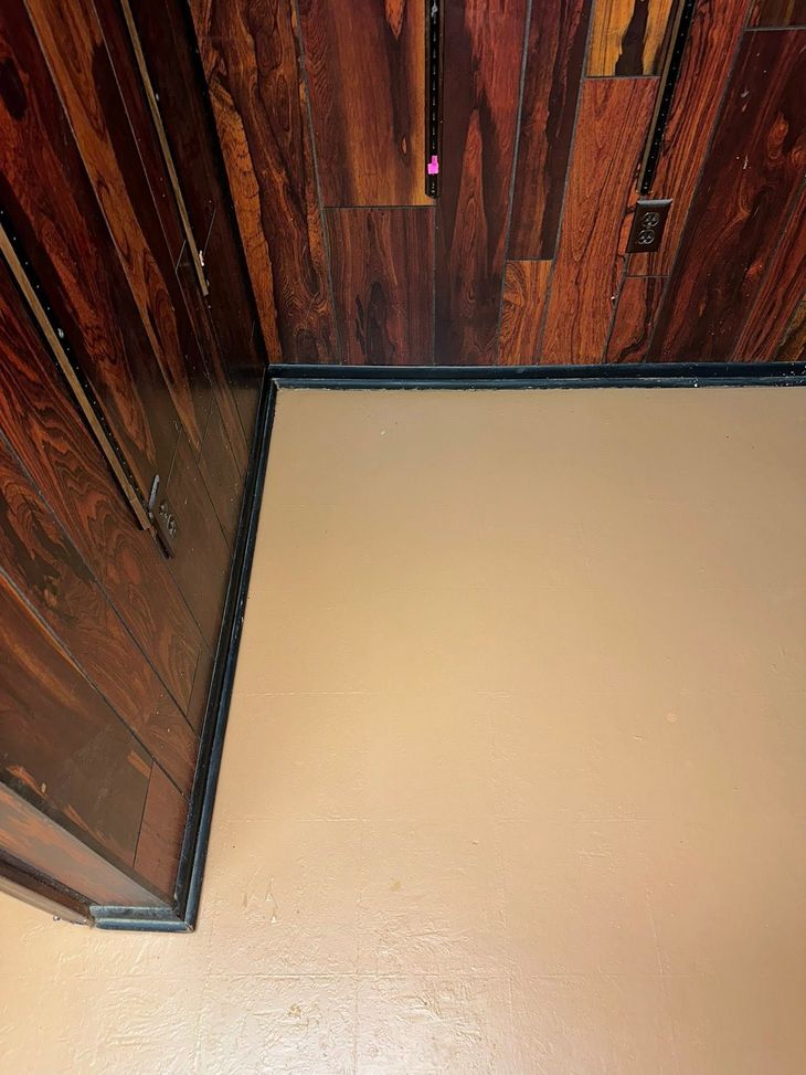 Rustic wooden wall panels and a beige floor in a small indoor corner.