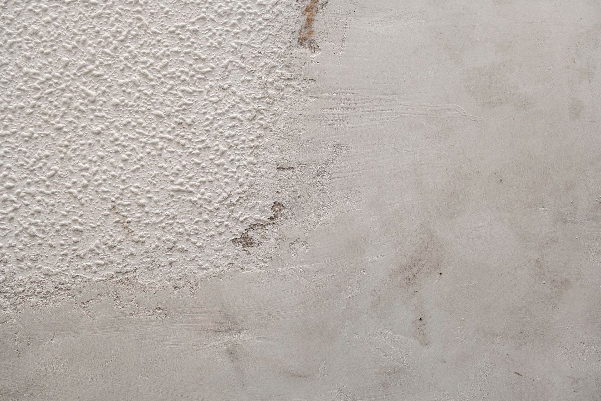 Close-up of a rough white textured wall with faint gray stains and wear marks