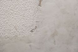 Close-up of a rough white textured wall with faint gray stains and wear marks