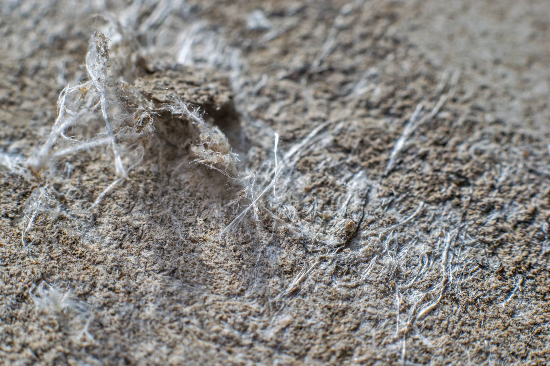 Close-up of weathered gray fabric with frayed white fibers and rough texture