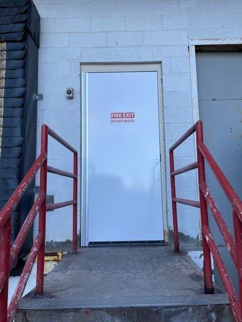 A white door with a red warning sign on it