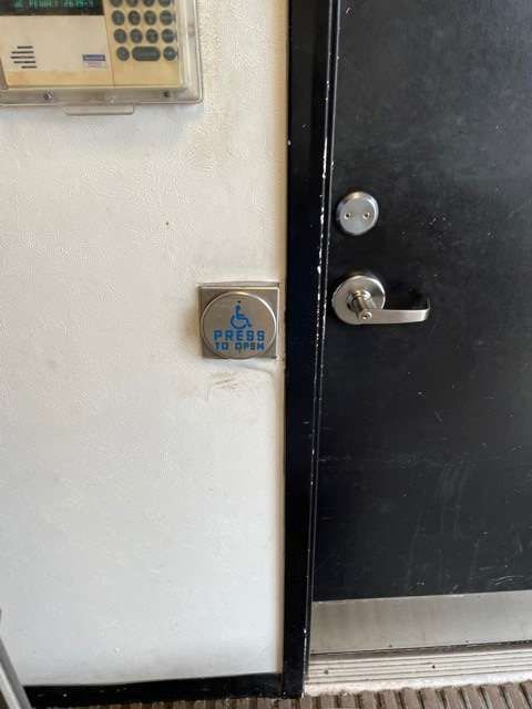 A black door with a keypad on the wall next to it.