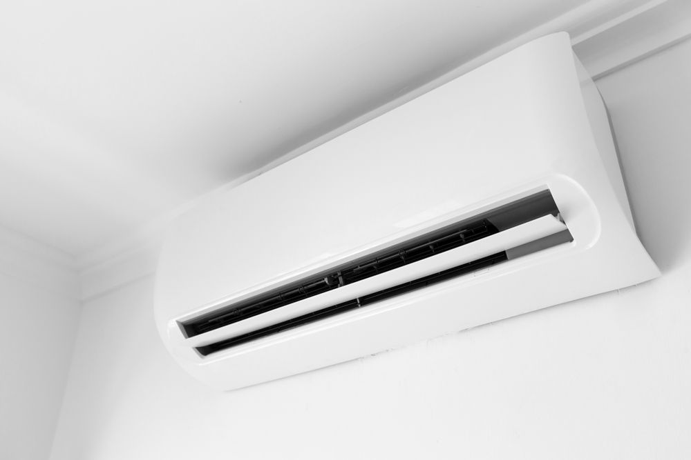White wall-mounted air conditioner with horizontal vents against a plain white wall.