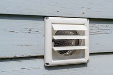 White dryer vent on a weathered, light blue siding.