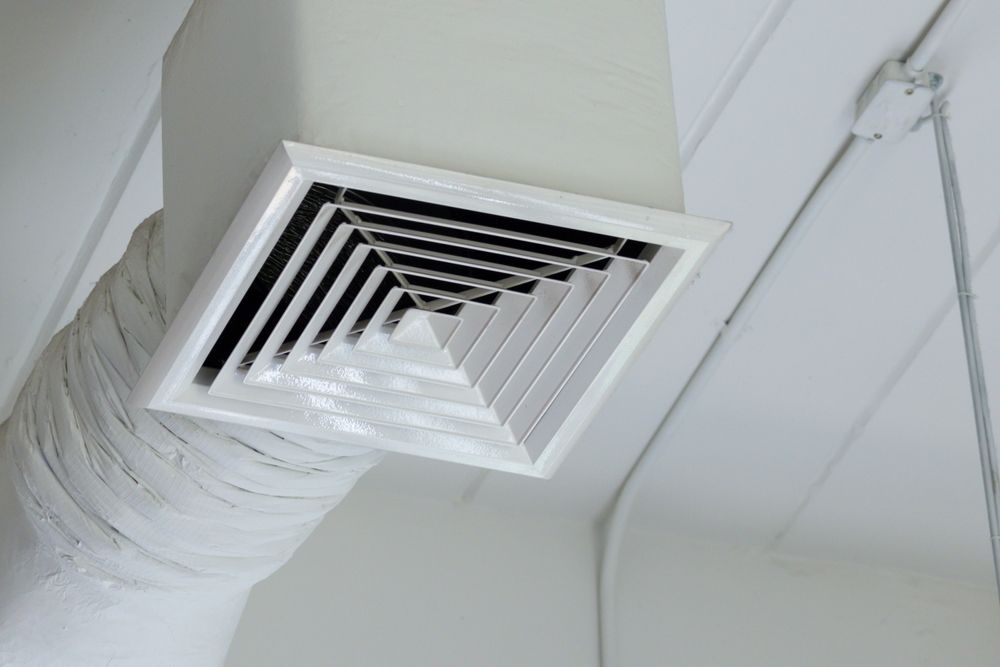 White square air vent in a ceiling, angled, with a large white duct.