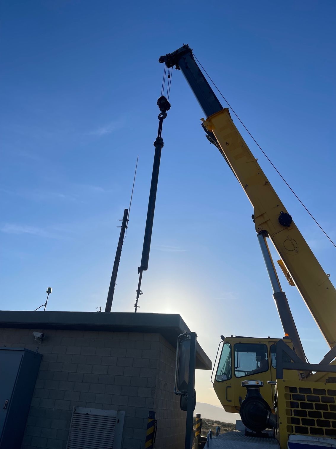 a yellow crane is lifting well pipe over a building