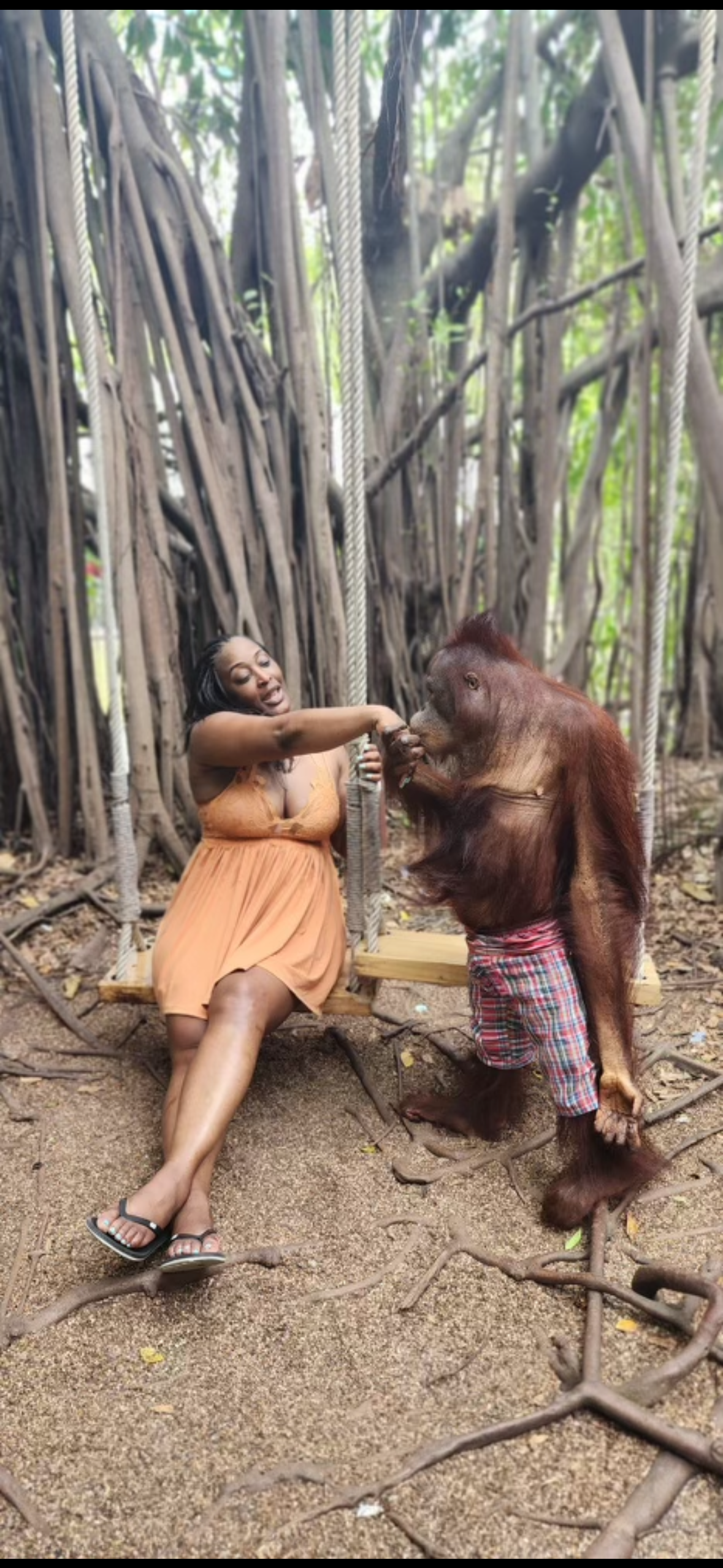 A woman is sitting on a bench next to a stuffed animal in the woods.