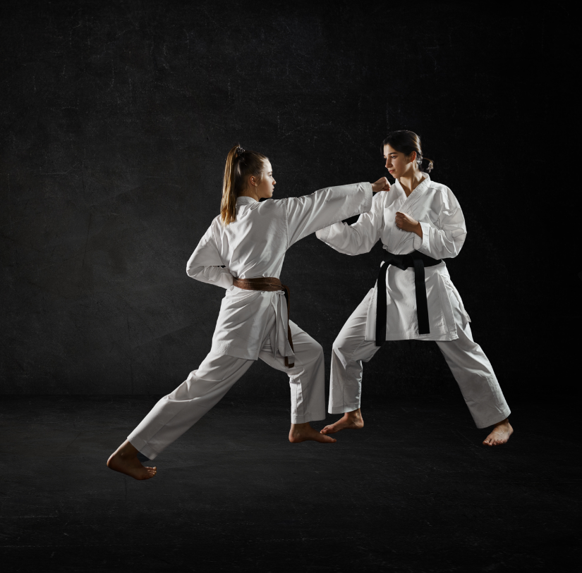 Two women are practicing karate in a dark room.