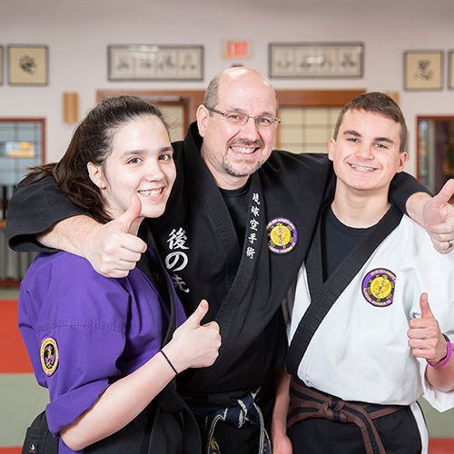 A group of people are posing for a picture and giving a thumbs up.