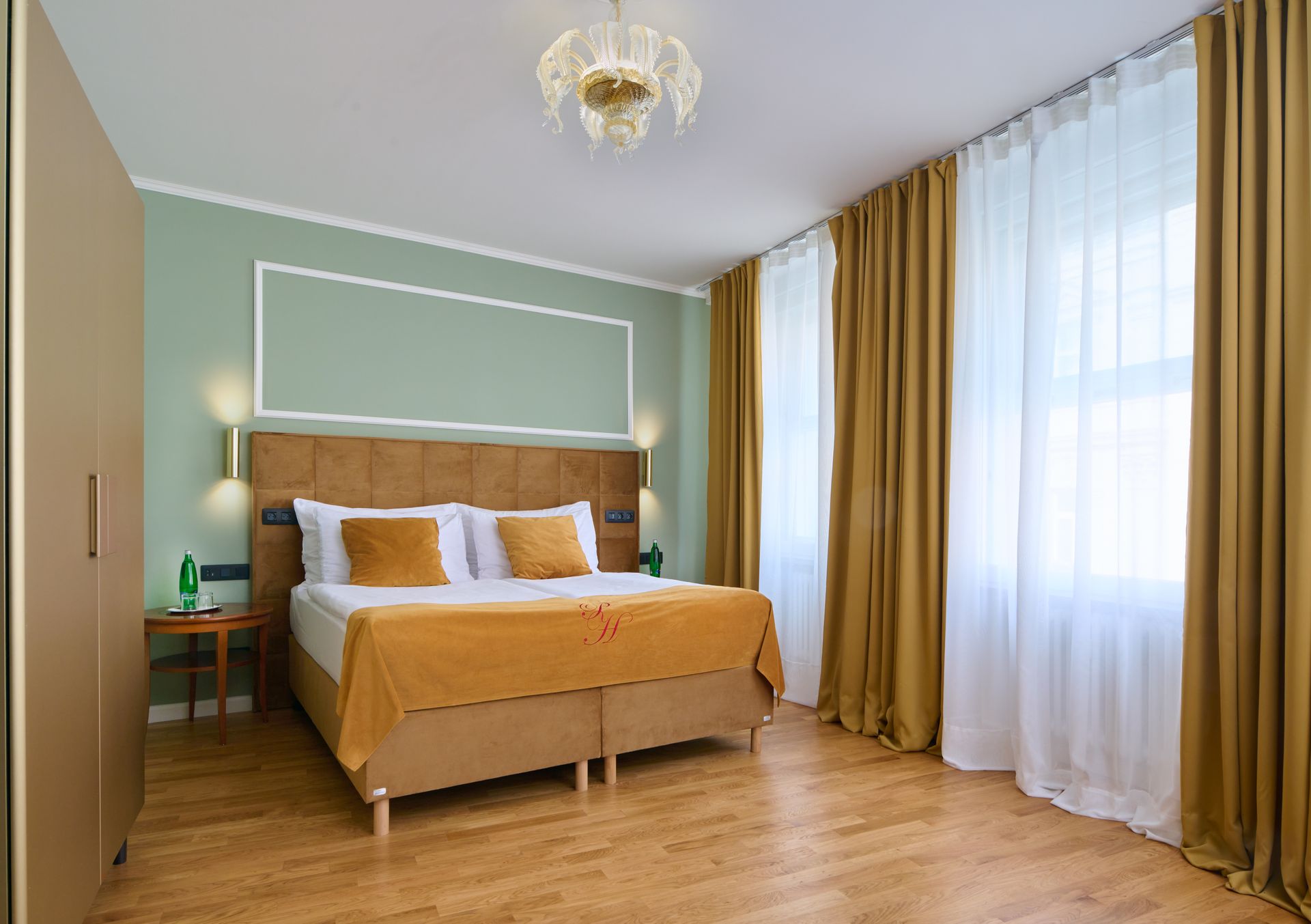Hotel bedroom with a double bed, yellow curtains and wood floor.