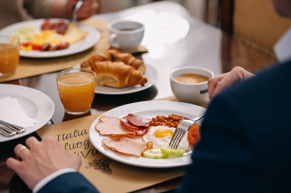 Tavolo per la colazione con piatti di cibo, croissant, caffè e succo d'arancia.