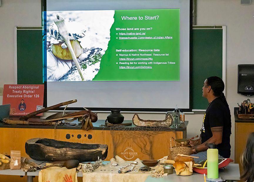 Man presenting with artifacts. Projection screen lists 