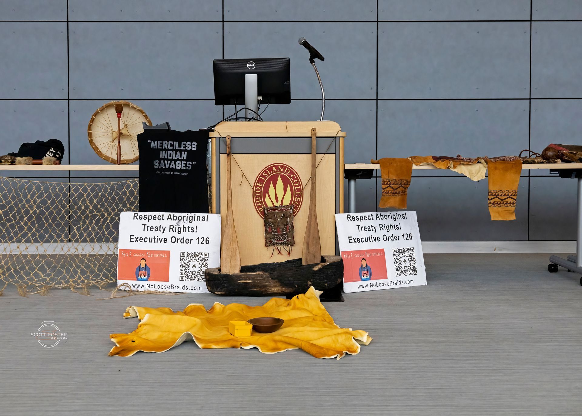 Display with Indigenous art, a podium, drum, and signs.