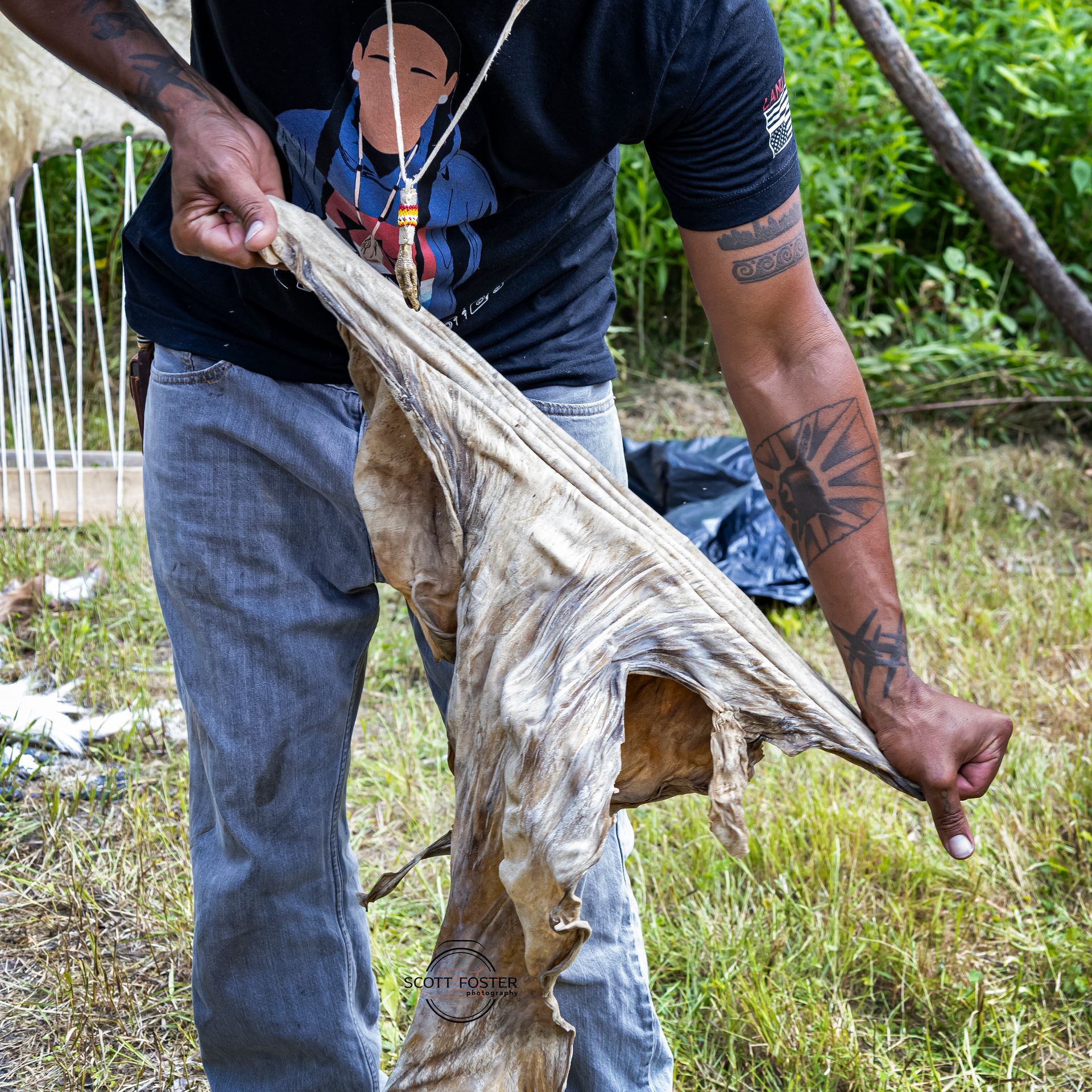 Person holding a tanned animal hide outdoors, stretching it with both hands.