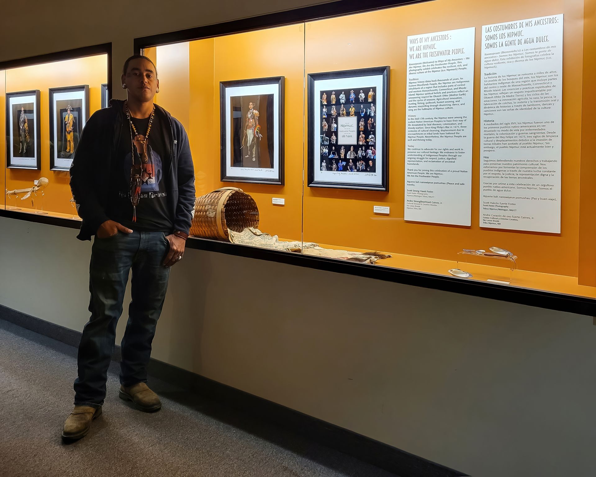 Man stands by display of framed artwork and handwritten notes in a gallery.