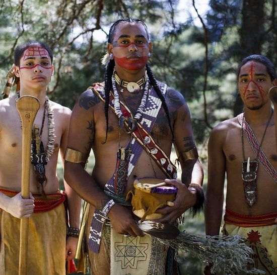 Three native men dressed in traditional attire.
