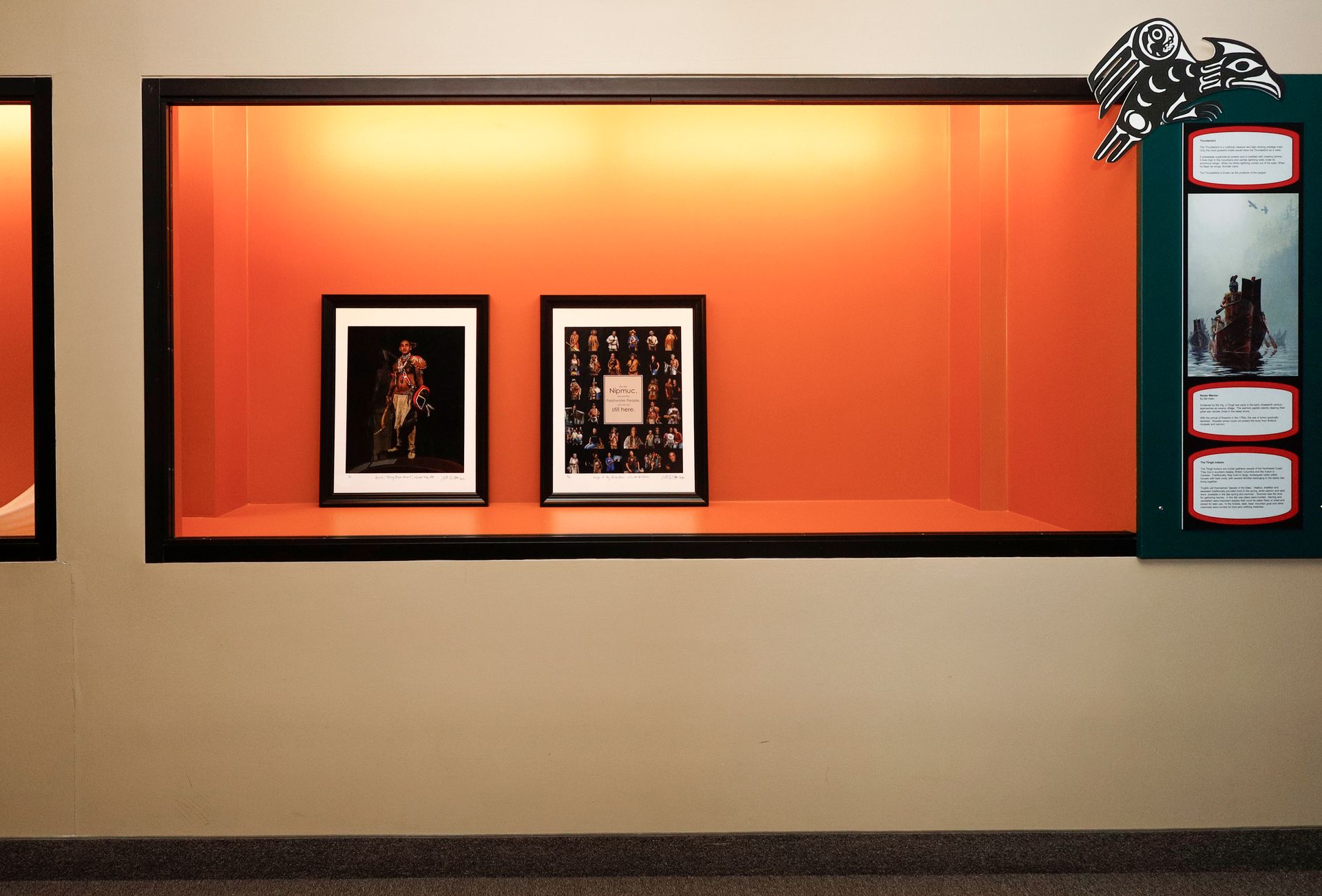 Wall display with two framed pictures against an orange backdrop, with a sign on the right.