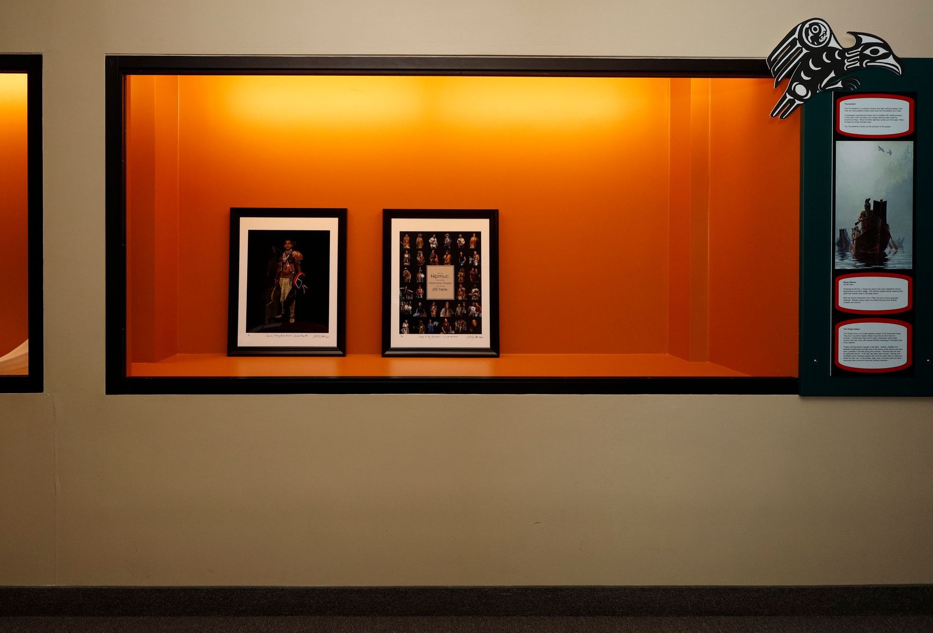 Two framed pictures displayed within an orange-lit wall niche.