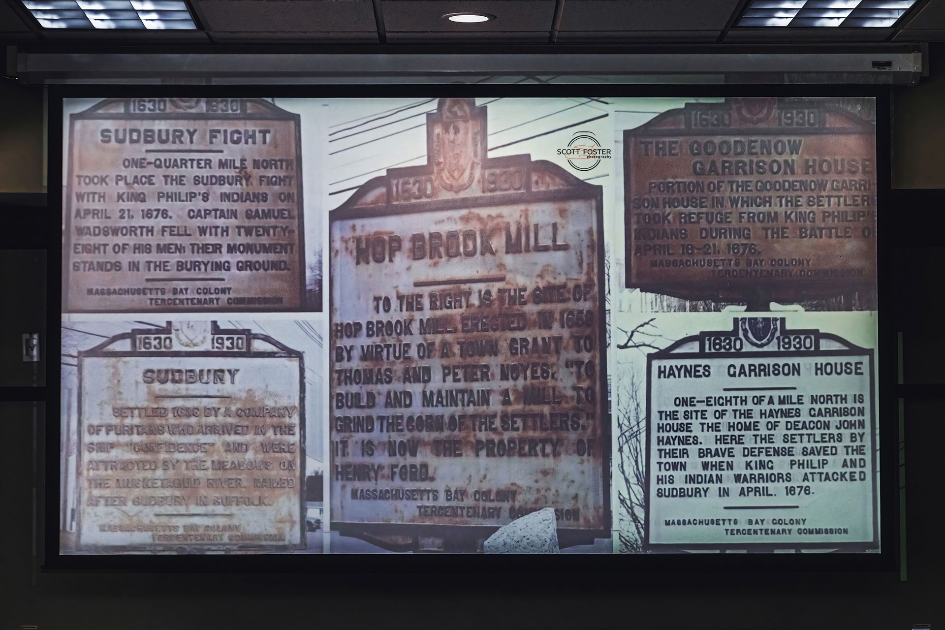 A projection screen displaying historical signs about Sudbury, including Hop Brook Hill and Sudbury Fight.