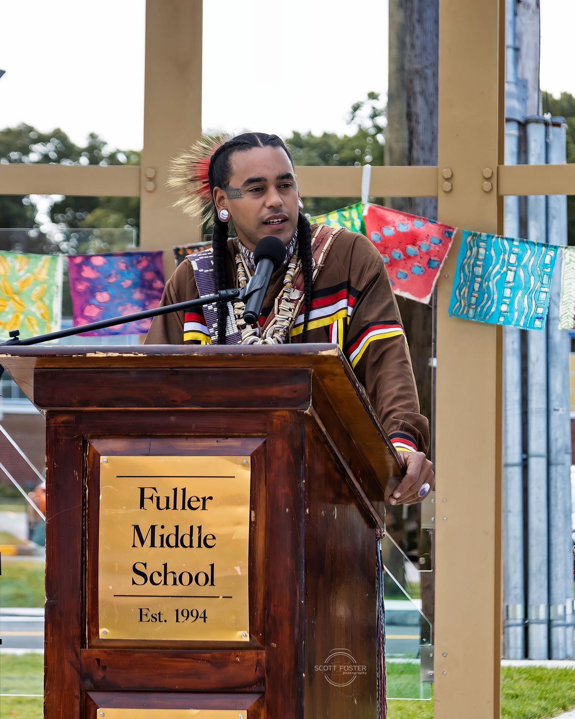 Man in traditional attire speaking at a podium with 