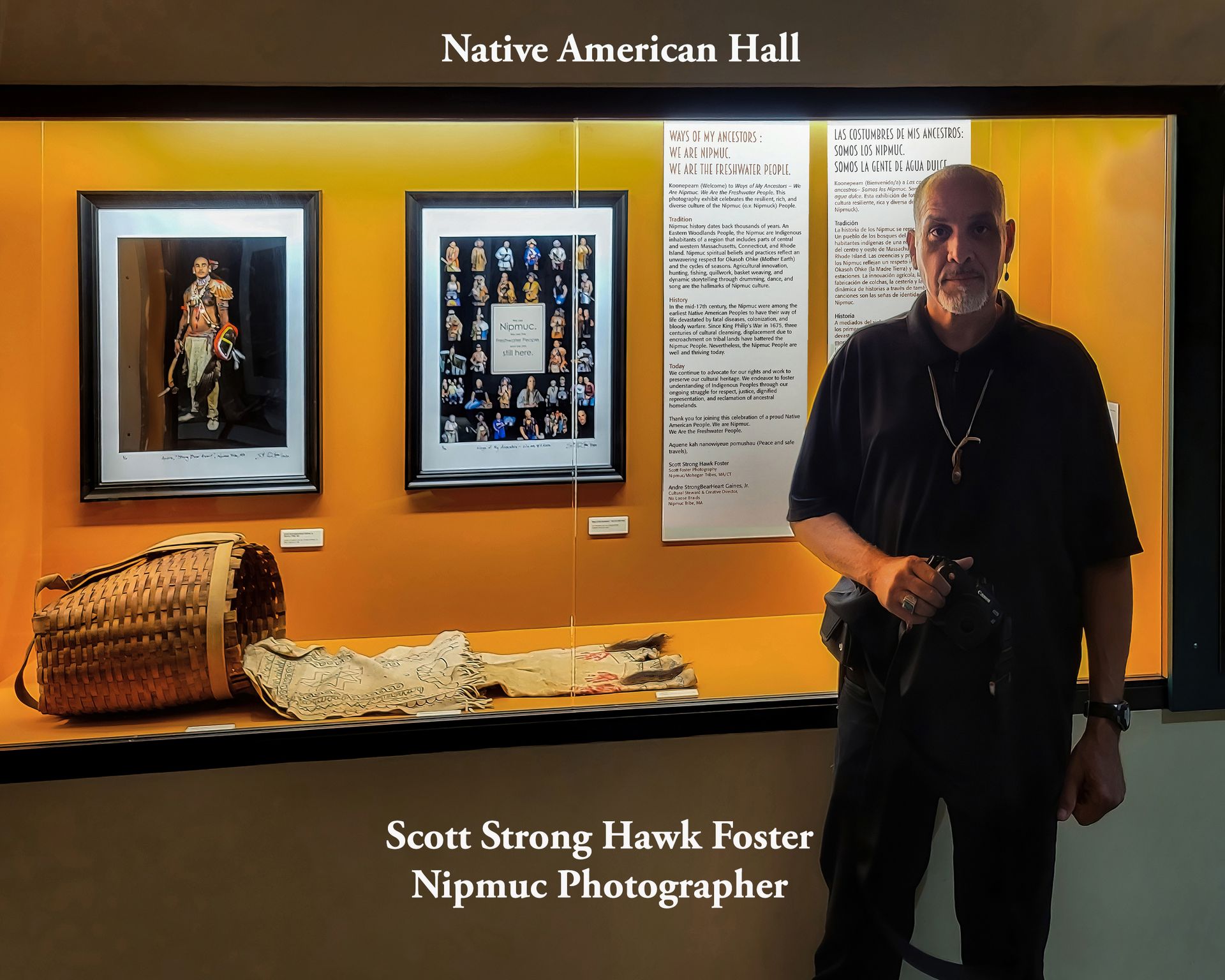 Man stands by Native American Hall display with framed photos and artifacts.