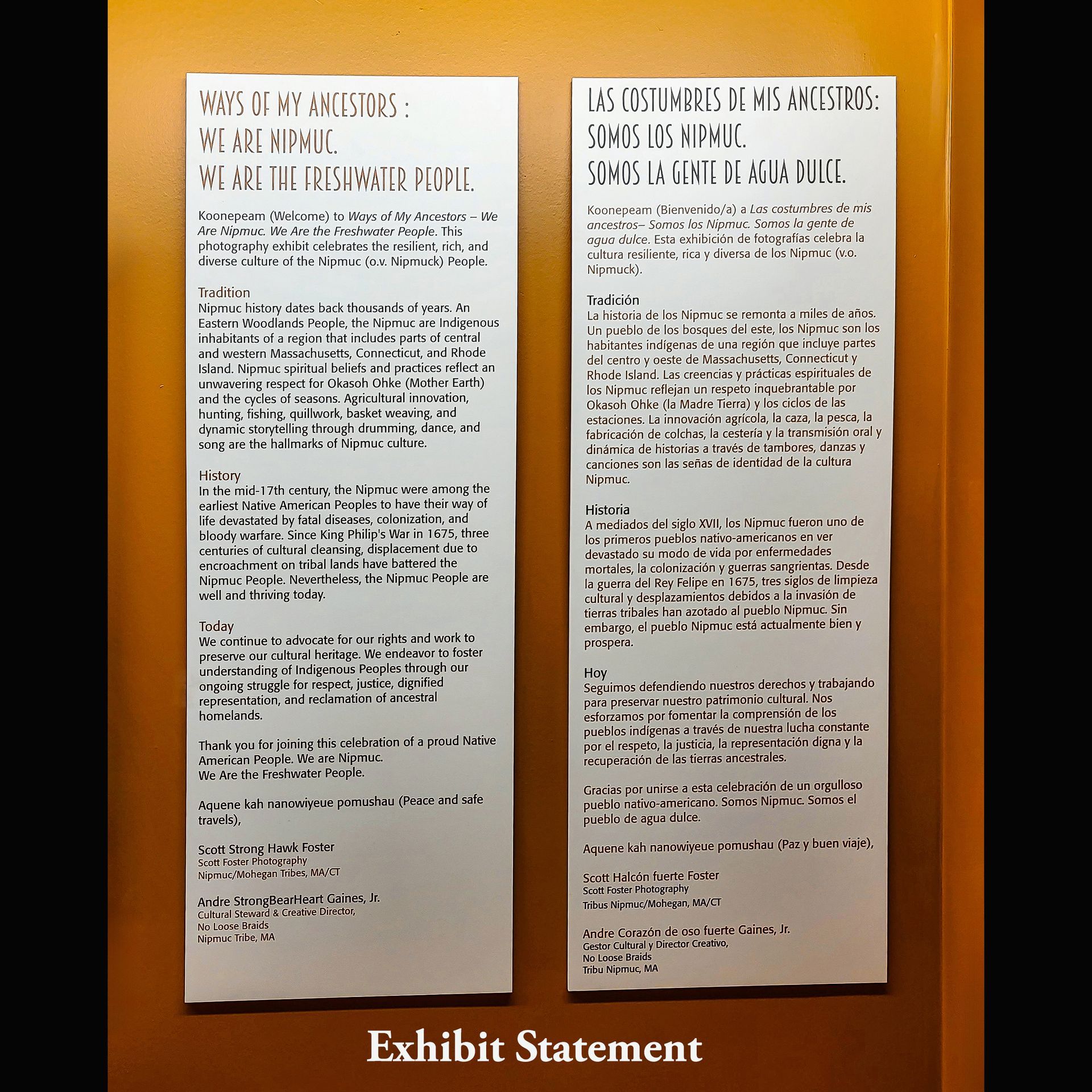 Two vertically oriented rectangular signs with black text on white backgrounds, on an orange-brown wall.