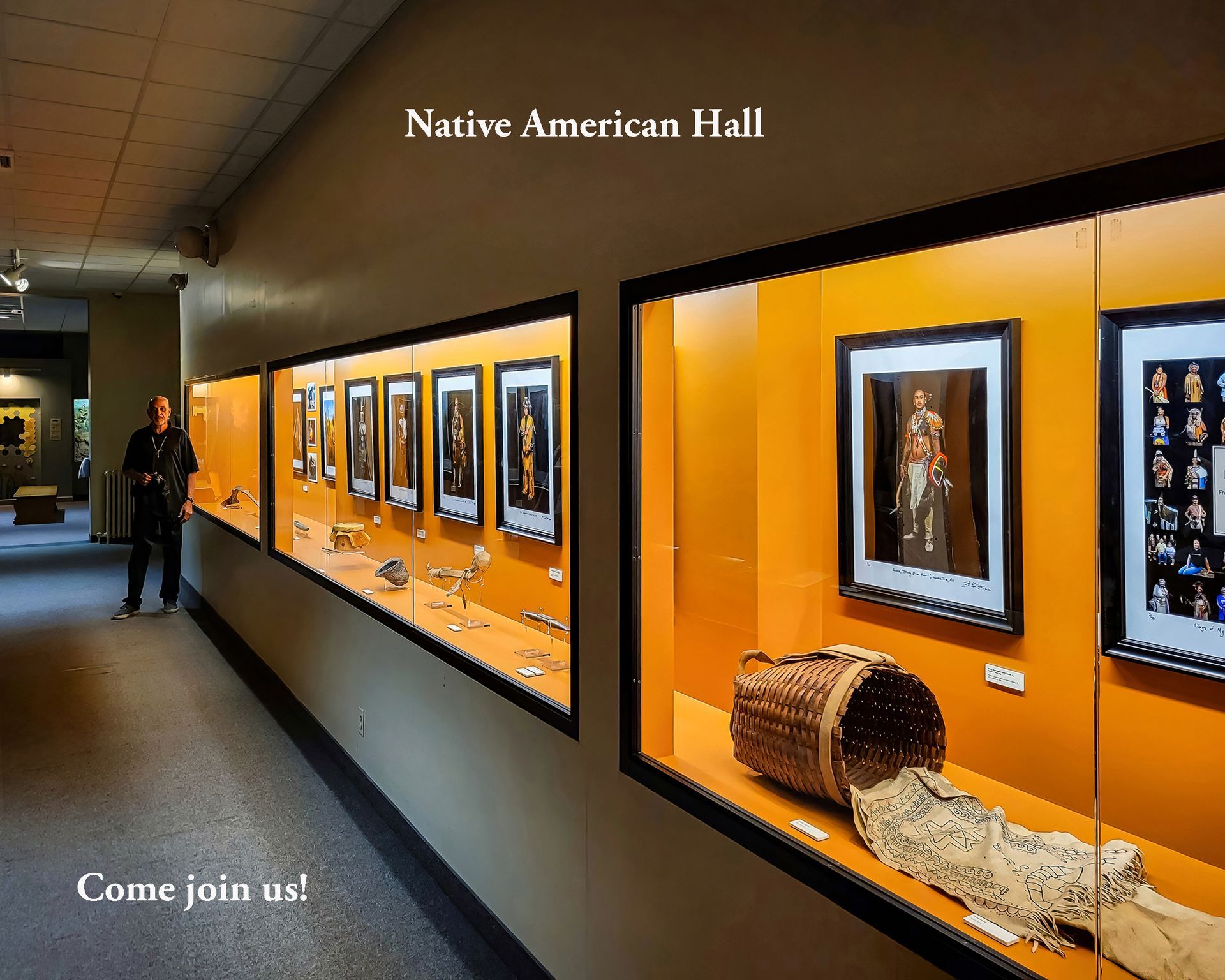 Museum hallway with display cases. A person stands near the exhibits. Orange walls.