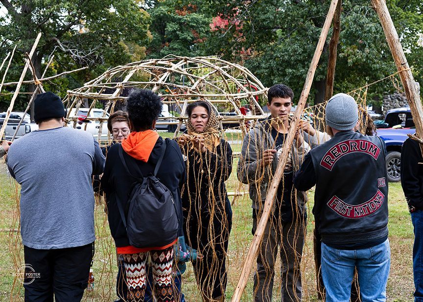 Group of people building a wooden dome structure outdoors.