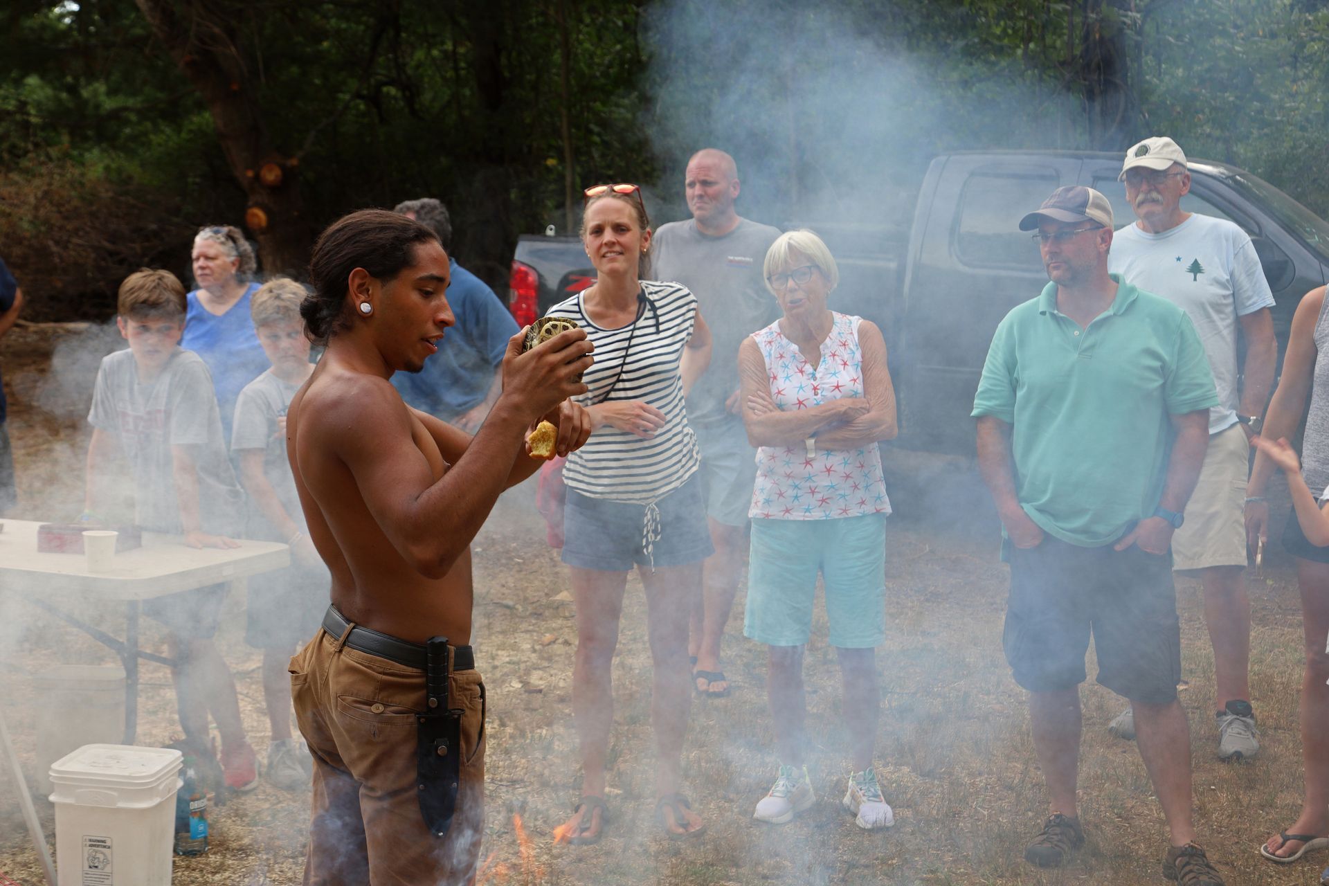 Man performing ceremony with smoke and a group of onlookers.