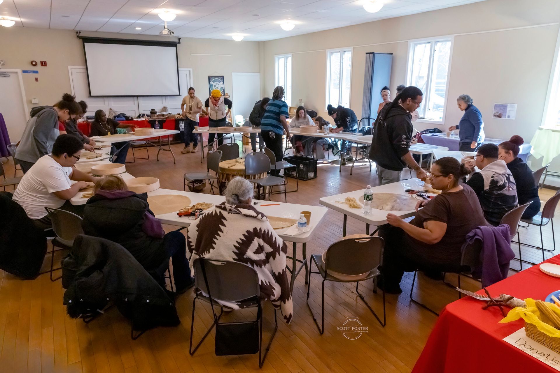 People crafting at tables in a brightly lit community hall.