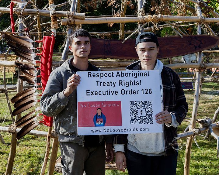 Two people holding a sign about Aboriginal Treaty Rights and Executive Order 126.