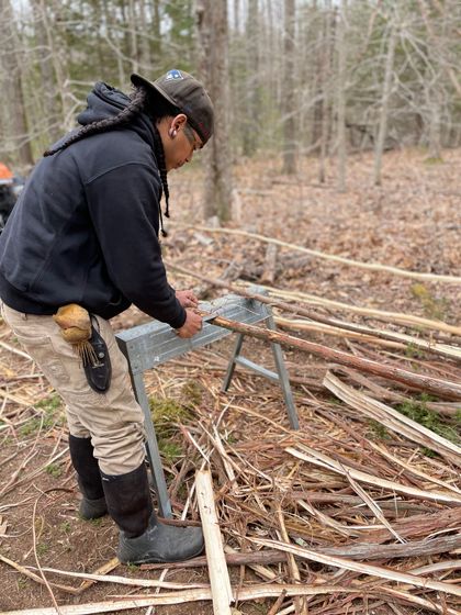 Andre is working with small trees and branches to show how to create a traditional building.
